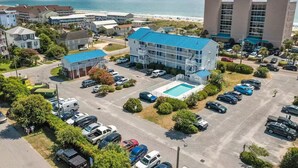 Een hotel met zwembad, parkeerplaats en uitzicht op het strand.