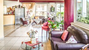A spacious lobby with a large seating area, a reception desk, and a view of the outdoors. - Alexandros Hotel (Agios Nikolaos)