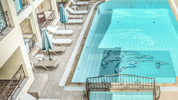 A swimming pool with dolphin designs, sun loungers, and a staircase leading to a balcony. - Alexandros Hotel (Agios Nikolaos)