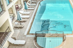 En säsongsöppen utomhuspool, parasoller och solstolar