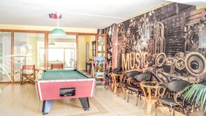 A billiards table in a room with a mural of musical instruments and the word "MUSIC" on the wall. - Alexandros Hotel (Agios Nikolaos)
