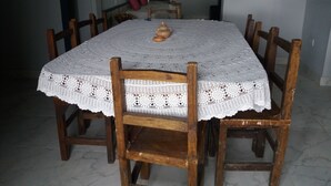 A dining table with a white lace tablecloth and wooden chairs.