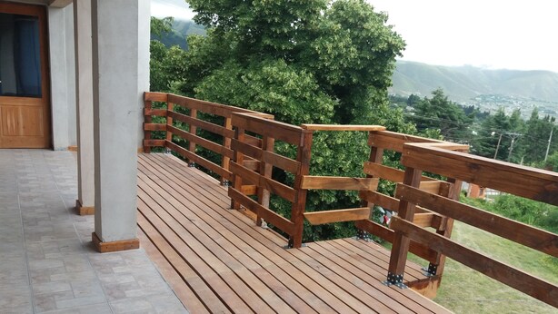 A wooden deck with a railing overlooking a green landscape.