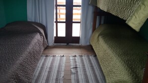 A room with two beds, a window with curtains, and a striped rug.