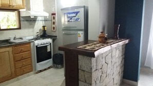 A kitchen with wooden cabinets, a stove, a refrigerator, and a stone island.
