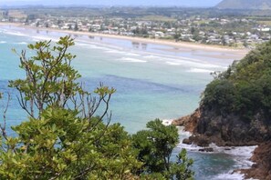 A coastal view with a beach, ocean, and a town in the background.