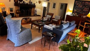 Un salon chaleureux avec une cheminée, des sièges confortables et diverses décorations murales.
