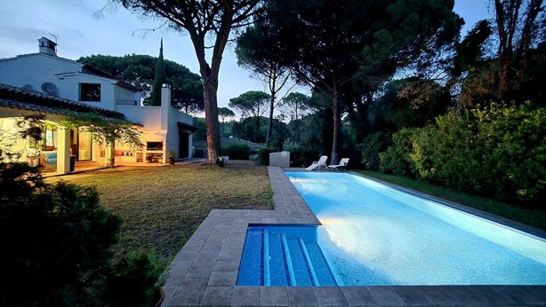 Une maison moderne avec une piscine, entourée d’une pelouse bien entretenue et d’arbres.