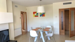 Un comedor moderno con una mesa de vidrio, sillas blancas y una lámpara colgante.