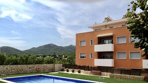 Una piscina con muro de piedra y zona ajardinada.