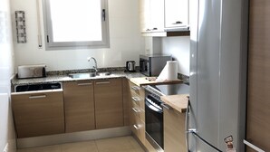 Una cocina moderna con armarios de madera, un refrigerador de acero inoxidable, un horno empotrado y un ventanal que proporciona luz natural.