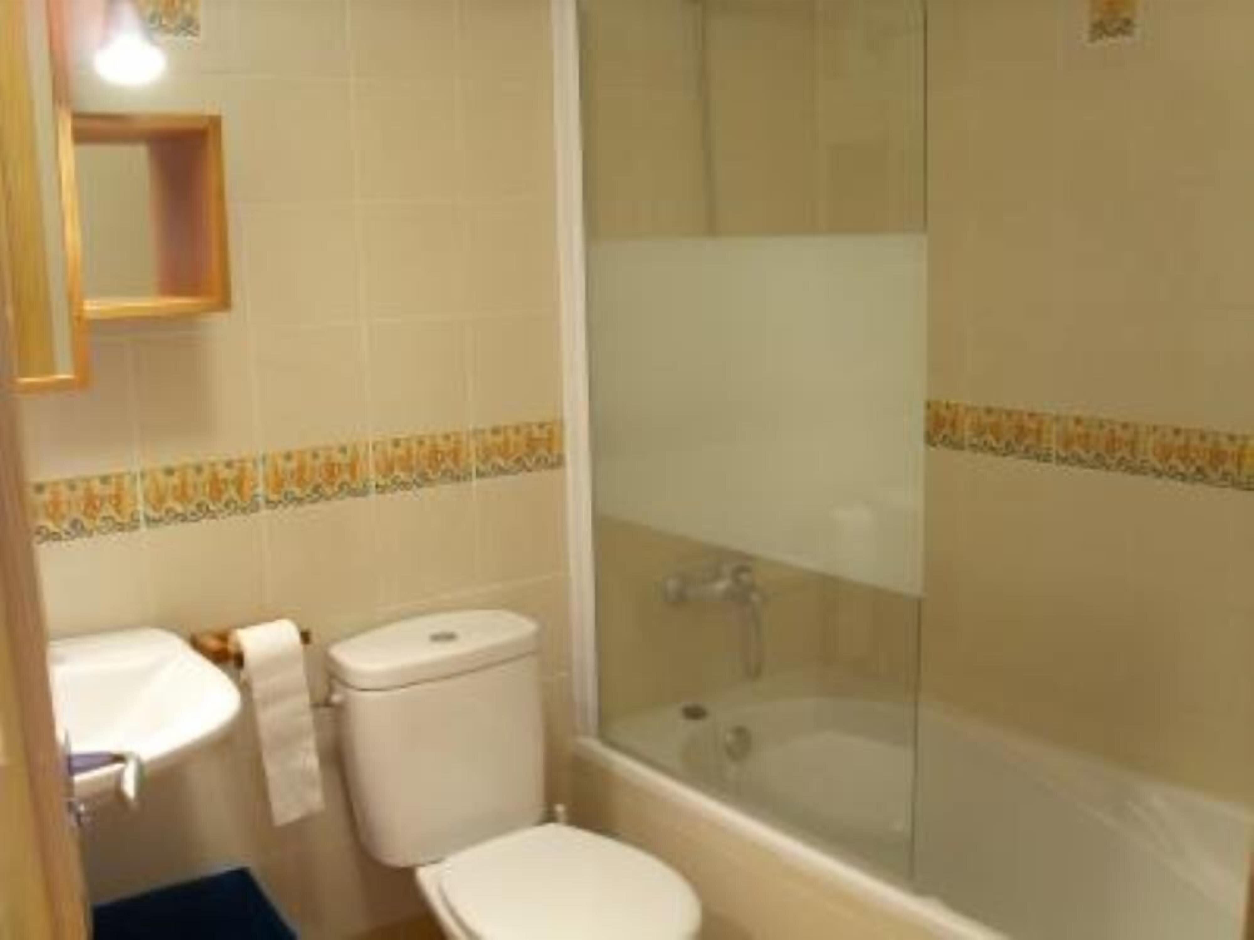 A bathroom with a toilet, sink, and glass-enclosed shower.