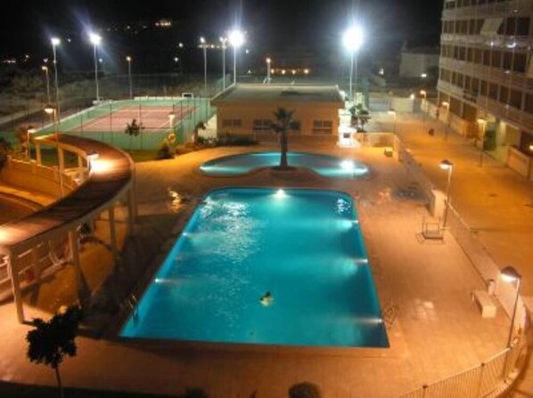 A swimming pool area with a slide and a building in the background.