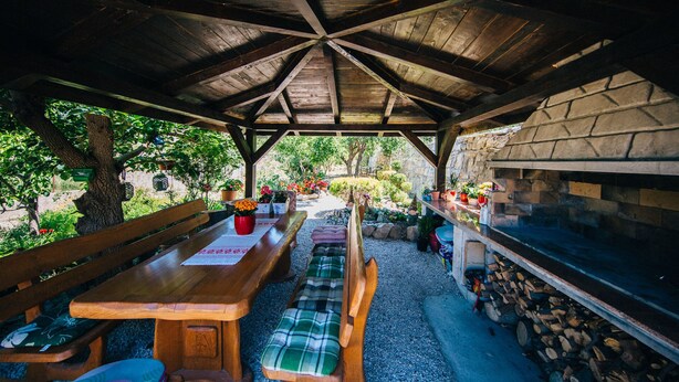 Un espacio de estar al aire libre con techo, bancos de madera y chimenea de piedra.