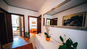 Un pasillo con un espejo, una cama y una planta.