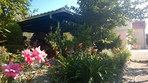 Un jardín con un pabellón, plantas en macetas y un edificio al fondo.
