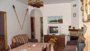 Un comedor con una mesa lista para cuatro personas, un televisor y una chimenea.