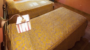 Habitación con dos camas, ventilador de techo y cortinas amarillas.