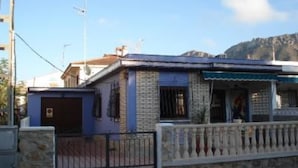 Un edificio residencial con fachada azul, entrada portonada y montañas al fondo.