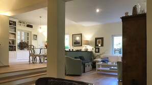 A spacious living room with a sofa, armchairs, and a coffee table. There is a bookshelf and a dining area in the background. - Charming Villa with pool near Rome  (Sacrofano)