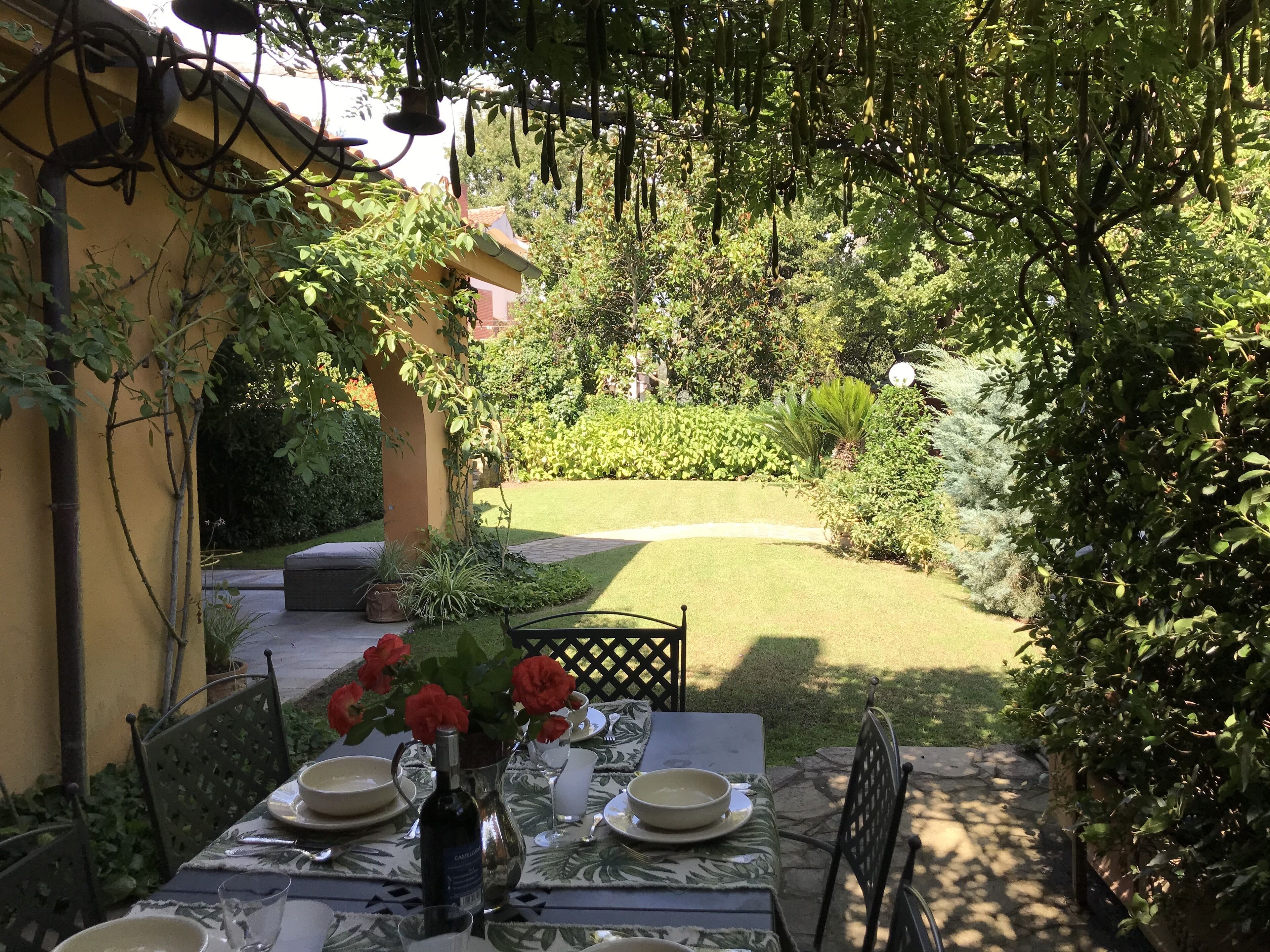 Ein Tisch draußen mit Blick auf einen Garten, der Rasen und verschiedene Pflanzen umfasst.