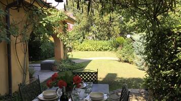 Ein Tisch draußen mit Blick auf einen Garten, der Rasen und verschiedene Pflanzen umfasst.