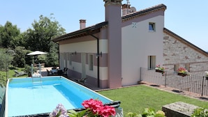 A swimming pool with a covered area, a stone building with a tiled roof, and a well-maintained lawn with flowers. - Villa with pool 10 minutes from Vicenza, garden, privacy, panoramic view (Isola Vicentina)