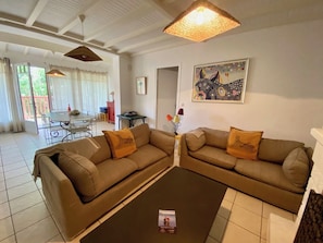 A living room with two sofas, a coffee table, and a dining area in the background. - Wooden house in Cap Ferret with big garden A0353 (Lège-Cap-Ferret)