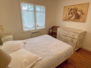 Ein Schlafzimmer mit Bett, Kommode, Stuhl und Fenster.