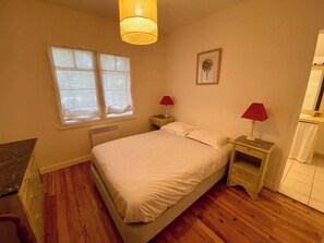 A bedroom with a bed, two bedside tables, a window, and a wall-mounted picture. - Wooden house in Cap Ferret with big garden A0353 (Lège-Cap-Ferret)