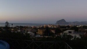 Vista de una piscina con escalera, con vista a un pueblo costero con edificios y una montaña al fondo.