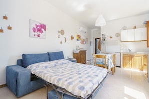 A compact living space with a bed, a sofa, a dining table, and a kitchen area. - Beautiful location overlooking the sea. (Erice)