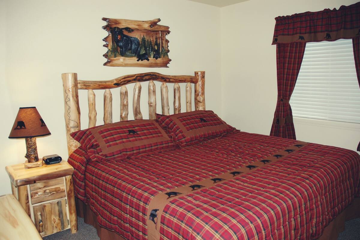 A bed with a plaid bedspread and a wooden headboard.