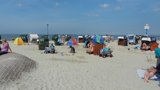 Een strand met tenten, ligbedden en een zandvlakte.