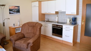 Een kleine keuken met witte kastjes, een ingebouwde oven en een koffiezetapparaat.