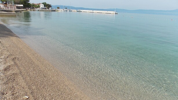 Une rive dégagée avec une plage de galets et une eau calme.