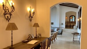 Un comedor con una larga mesa de madera, dos lámparas fijadas a la pared y un candelabro.