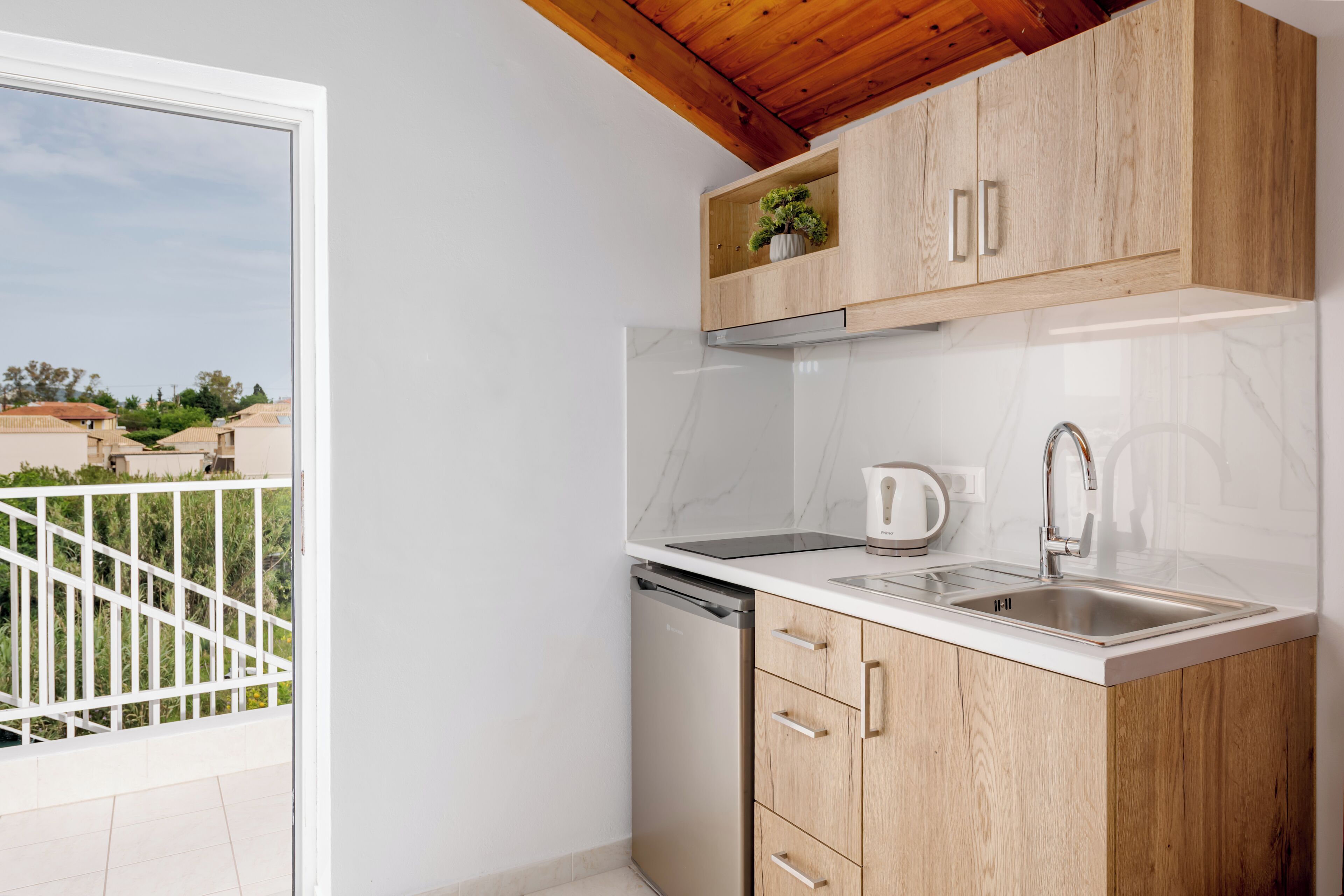 Una cucina compatta con mobili in legno, un piano di lavoro bianco e una lavastoviglie integrata.