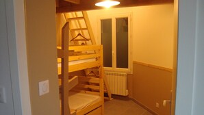 A small, narrow room with a bunk bed, a radiator, and a window. - House close to all shops (Saint-Denis-d'Oléron)