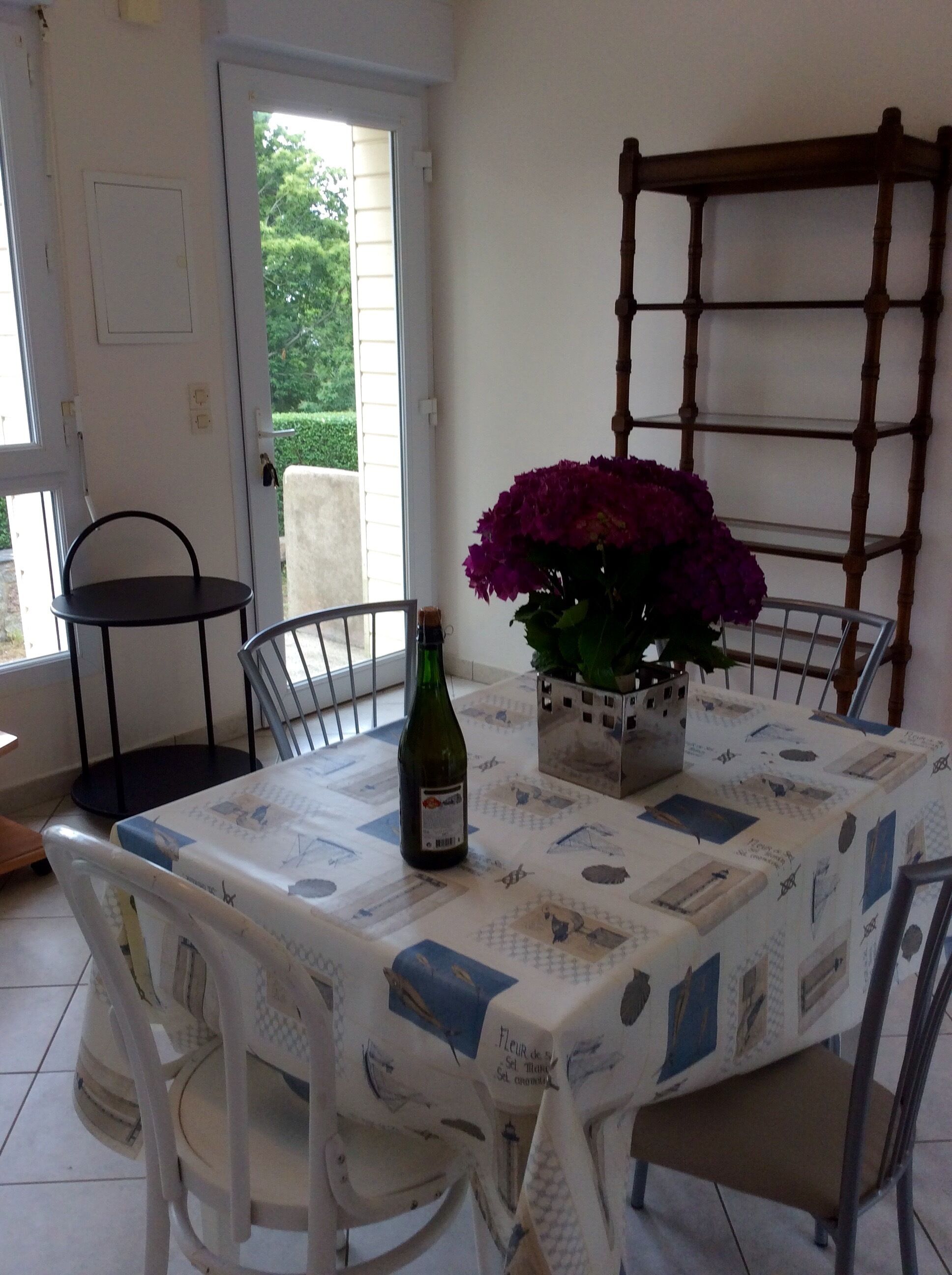 A dining area with a table set for two, a bottle of wine, and a potted plant.