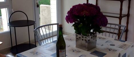 A dining area with a table set for two, a bottle of wine, and a potted plant.