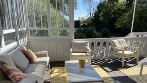 En solig uteplats med en vit soffa, ett gult bord och en vit stol.