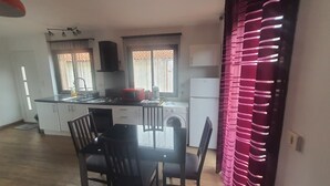 A compact kitchen with a dining area, a washing machine, and a refrigerator.