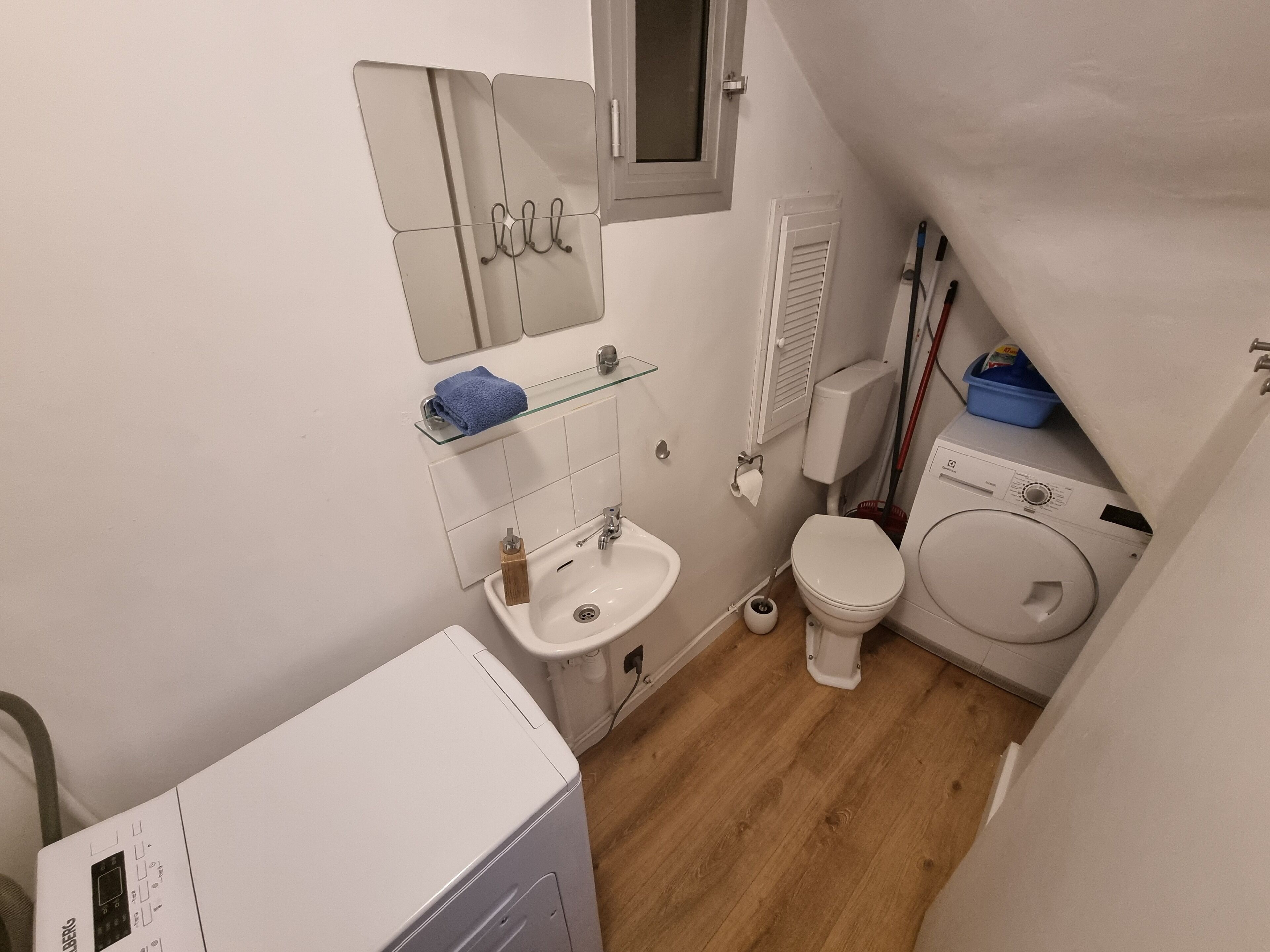 Une petite salle de bain comprenant un lavabo, des toilettes et un lave-linge.
