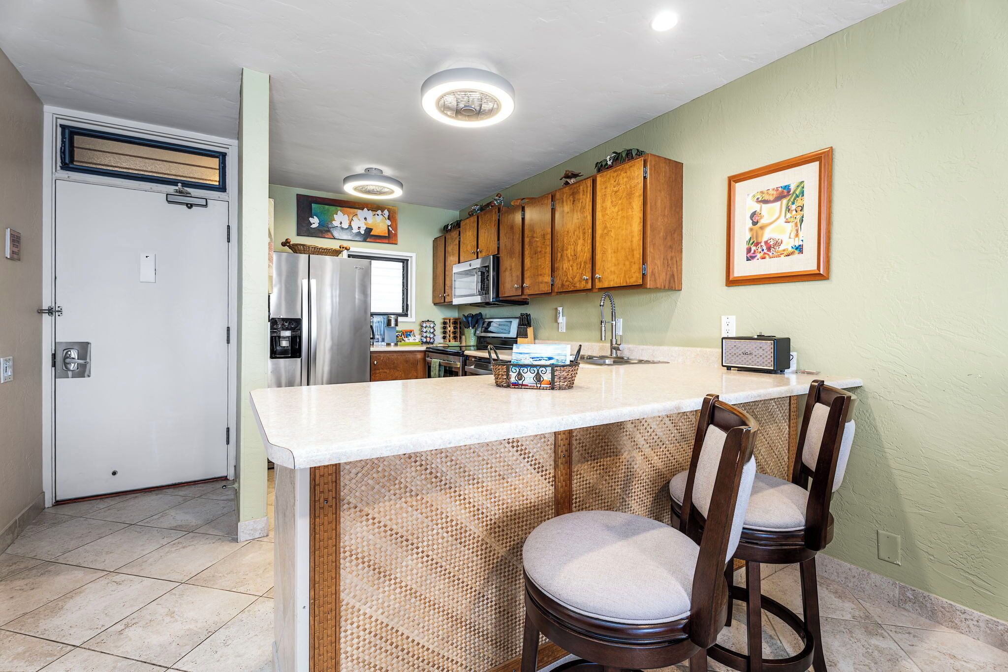 A kitchen with a central island, wooden cabinets, a microwave, and a refrigerator.