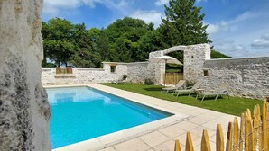 Una piscina con paredes de piedra y valla de madera.
