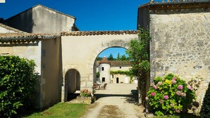 Un arco de piedra que da paso a un patio con un edificio al fondo.