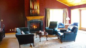 Una sala de estar acogedora con chimenea, sofás de cuero y un gran ventanal.