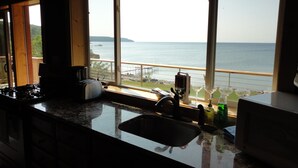 Una cocina con un amplio ventanal que da a una masa de agua y una isla distante.