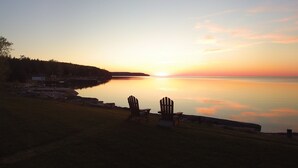 Escena tranquila junto al lago, con dos sillas Adirondack mirando al atardecer.